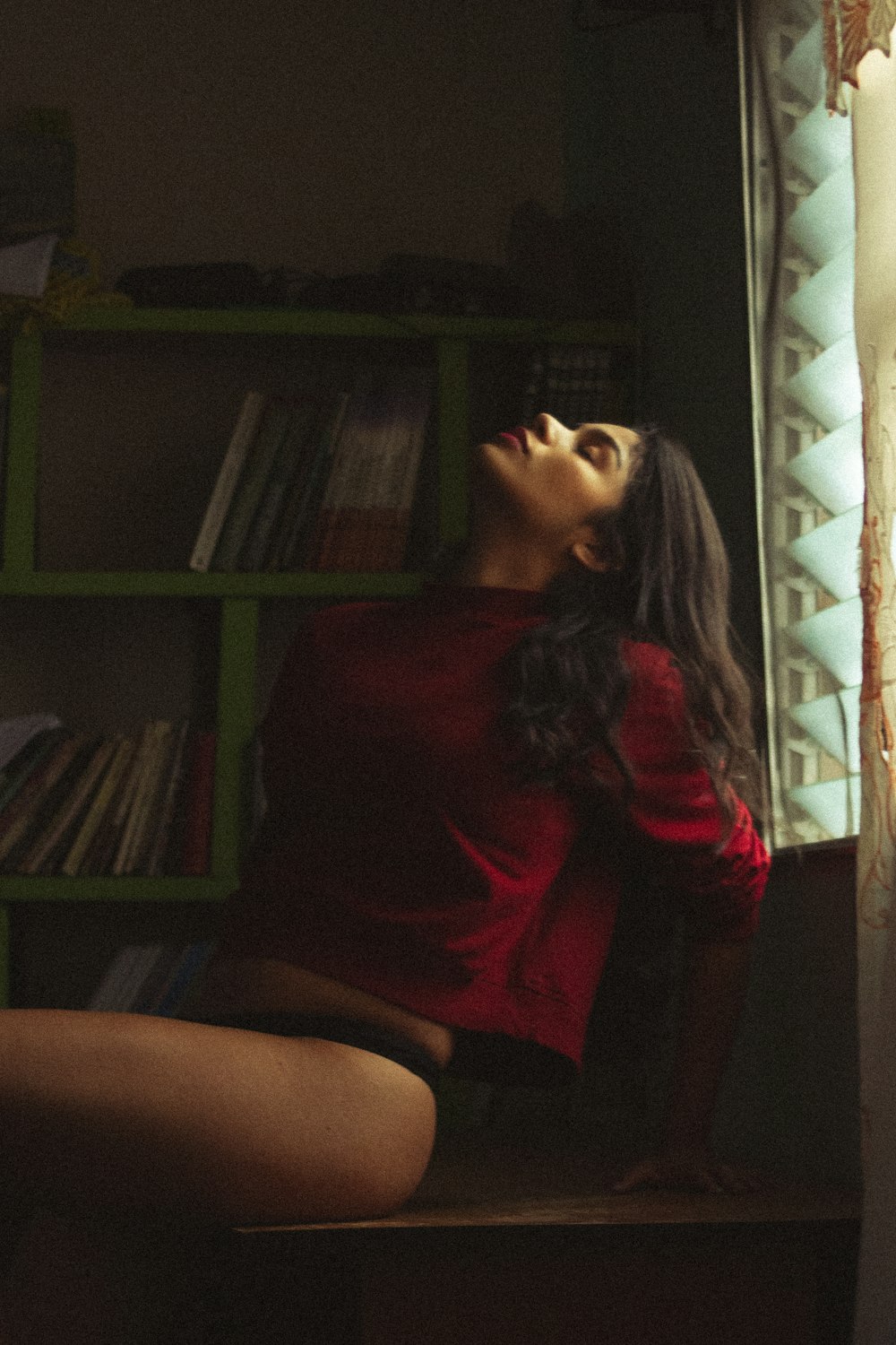 a woman in a red shirt is sitting on a shelf