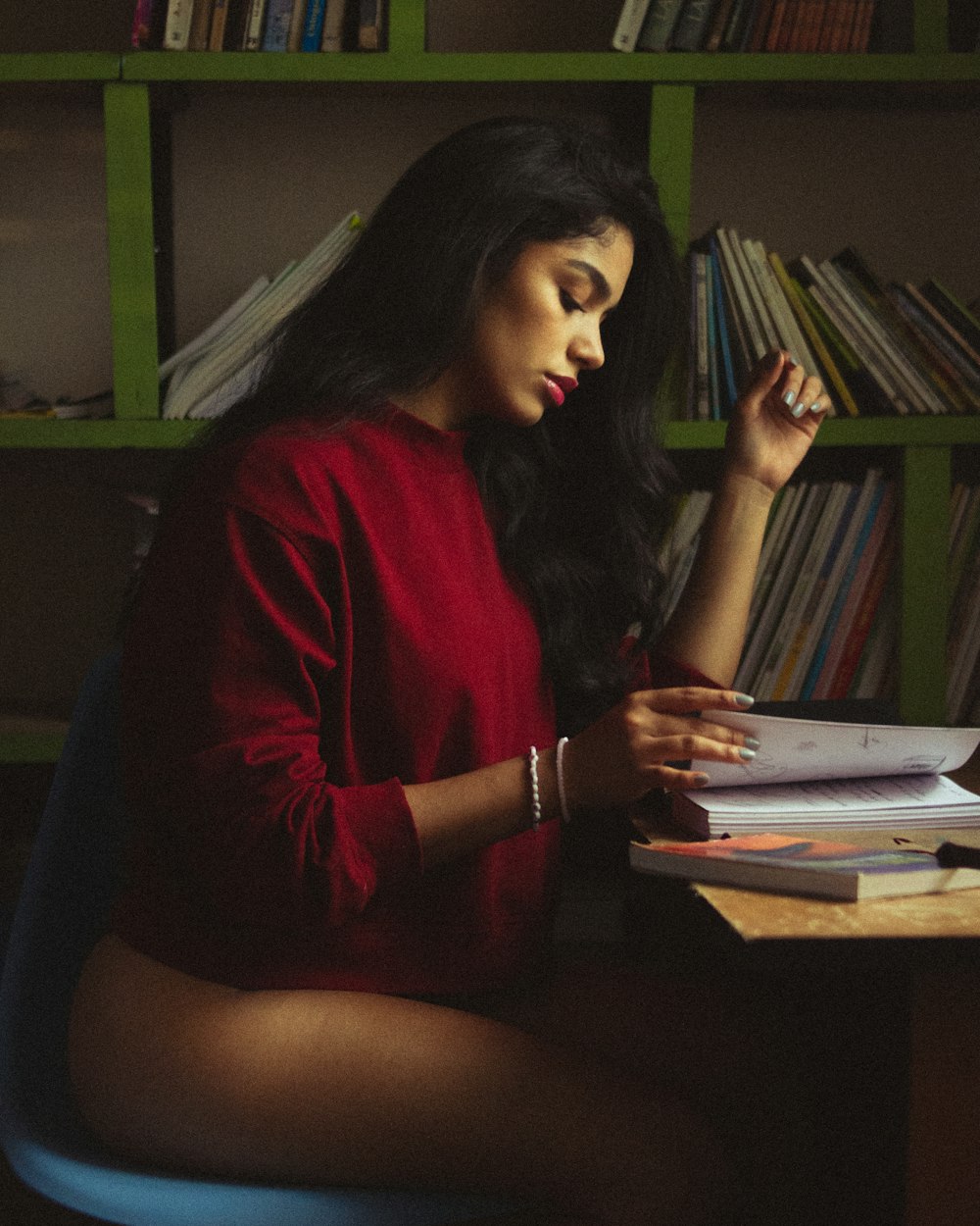 a woman sitting at a desk in front of a bookshelf