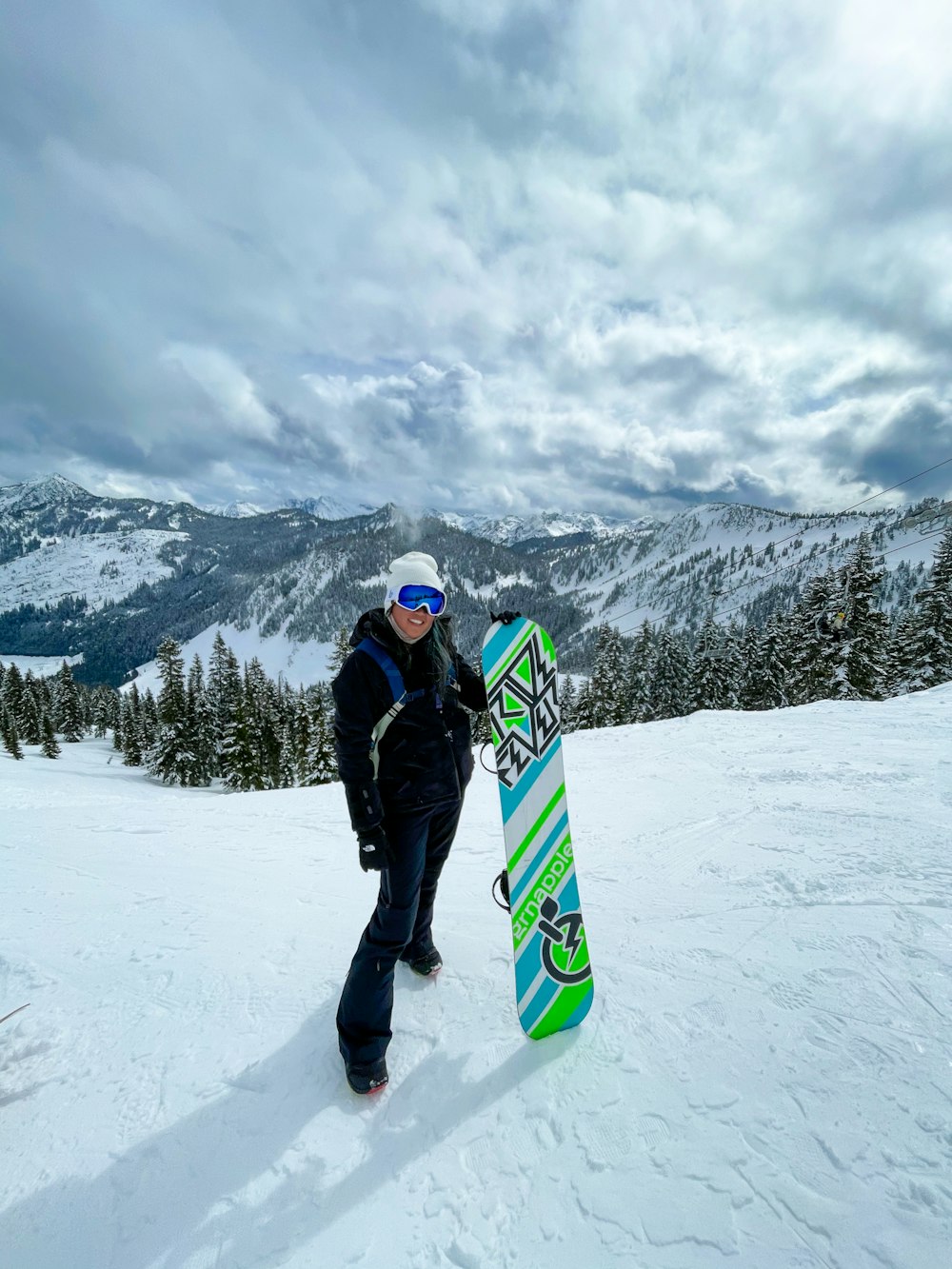 man in black jacket and blue pants holding green and yellow snowboard on snow covered ground