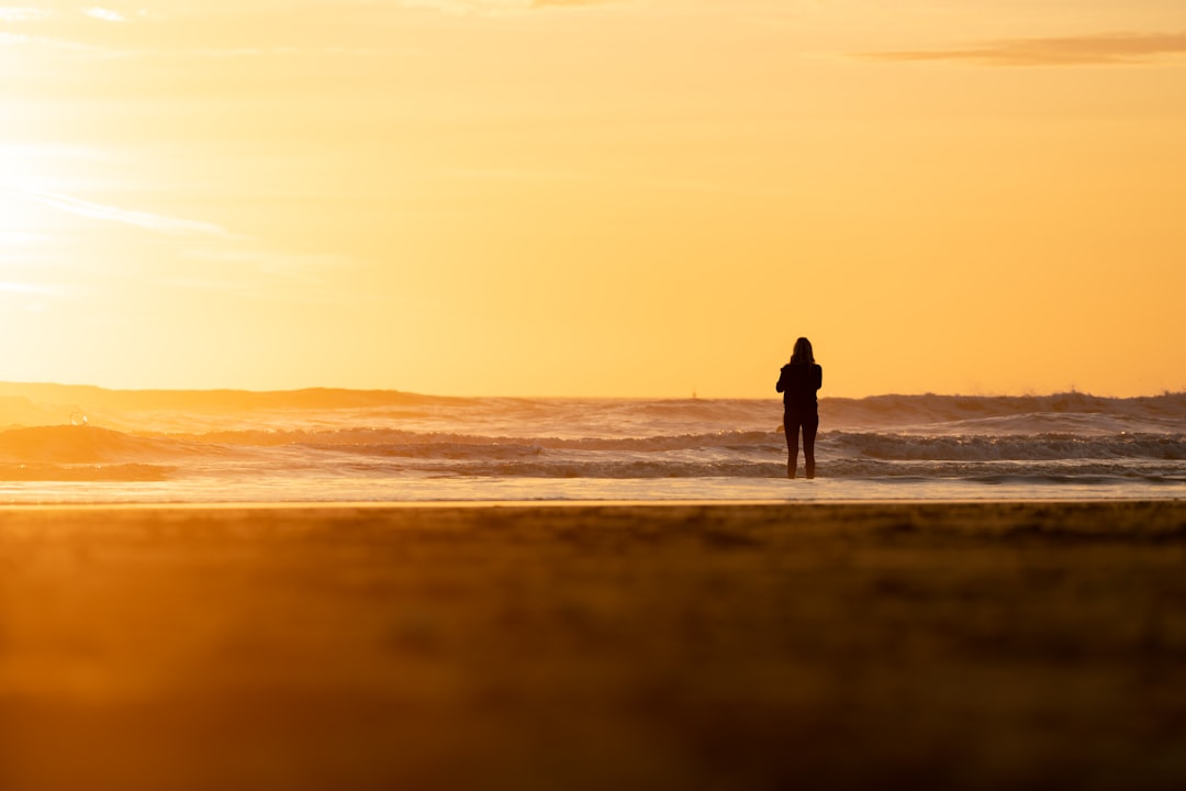 silhouette of man and woman walking on beach during sunset