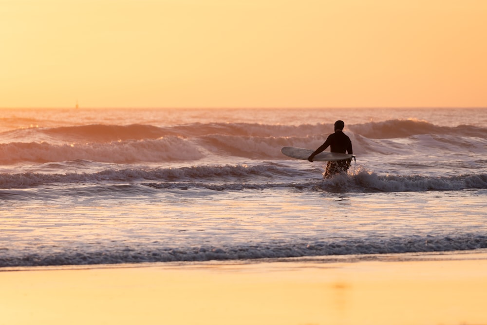 夕暮れ時に海の波でサーフィンをする男