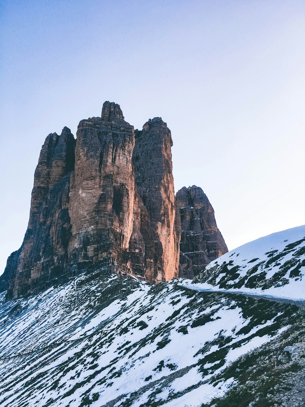 Montaña rocosa marrón cubierta de nieve durante el día