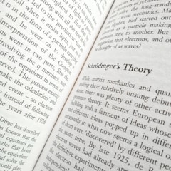 A close-up view of an open book displaying text. The title 'Schrödinger's Theory' is prominently featured, surrounded by content discussing matrix mechanics and quantum theory. The pages are filled with dense text in a formal typeface.