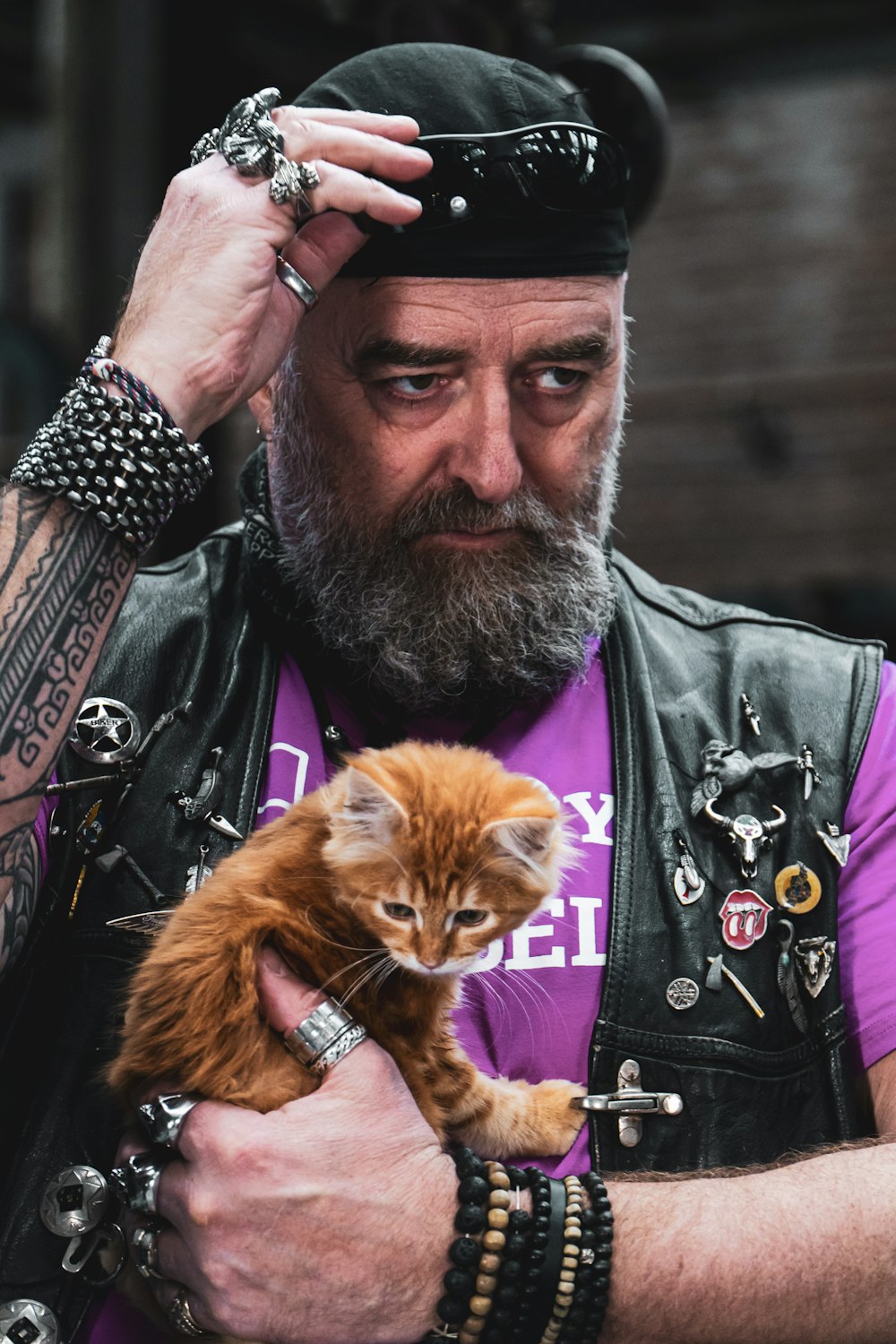 man in black and white shirt holding orange tabby cat