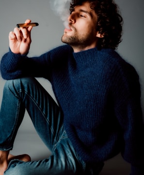 man in blue sweater and blue denim jeans sitting on blue couch