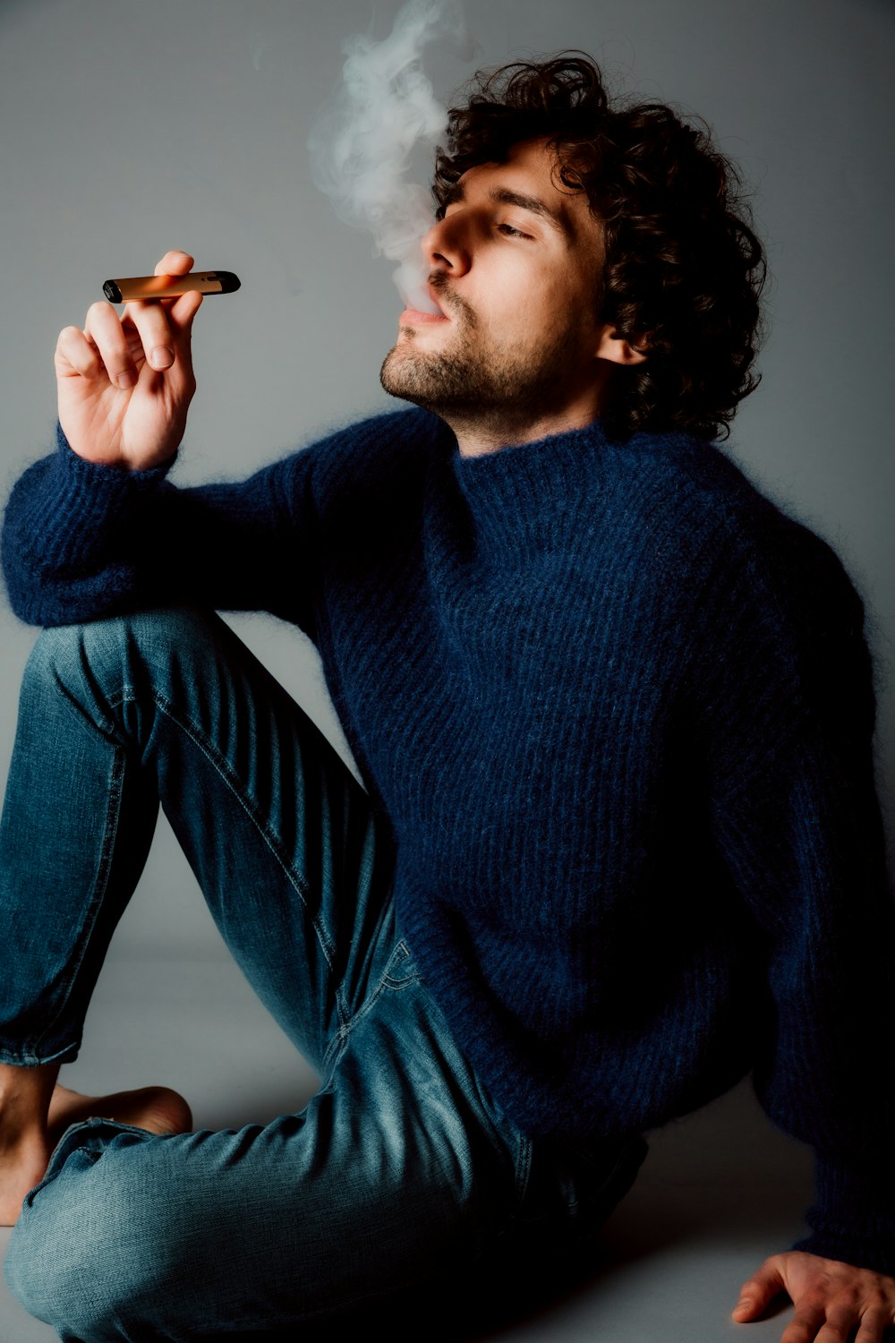 man in blue sweater and blue denim jeans sitting on blue couch