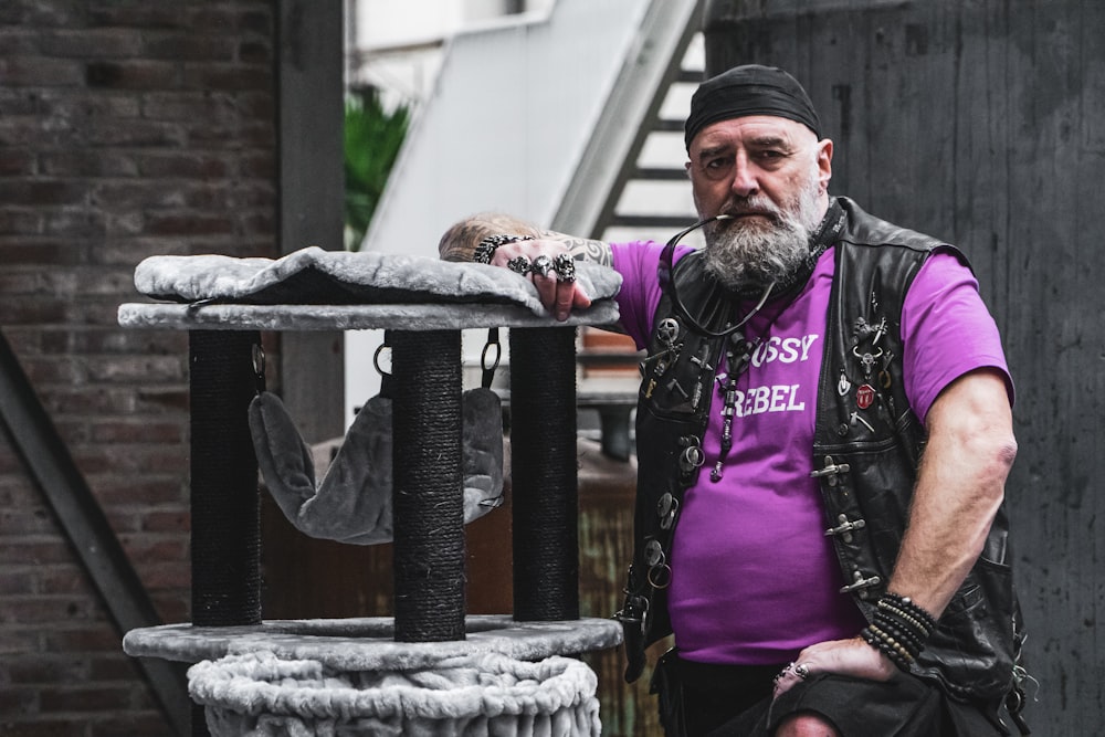 homme en chemise à manches longues violette tenant un sac en plastique blanc