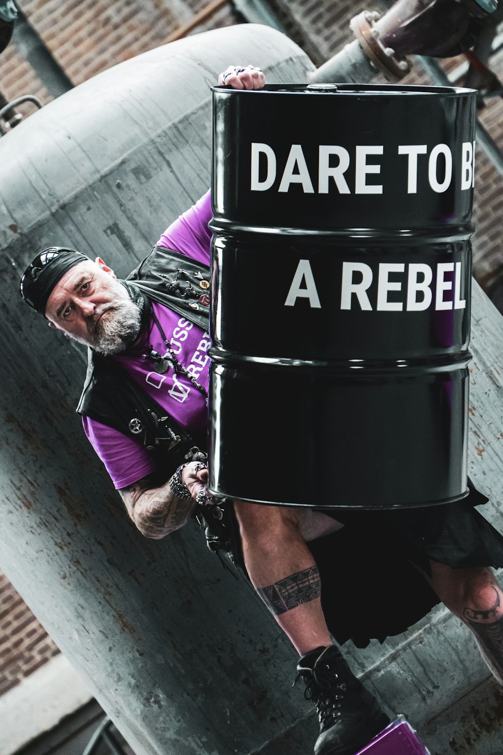 Homme en veste violette et pantalon noir assis sur une poubelle noire