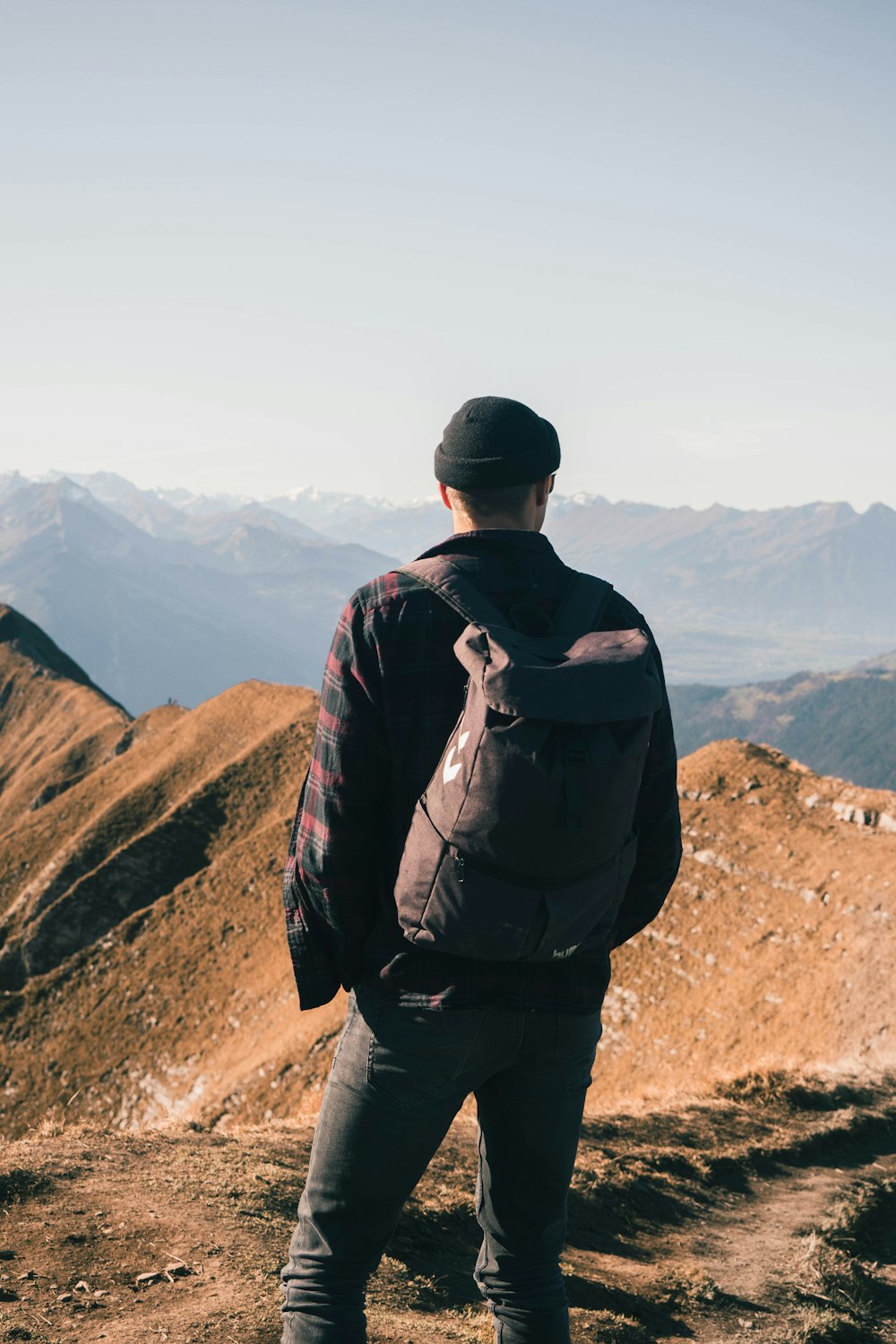 man in black jacket and black pants standing on brown rock mountain during daytime