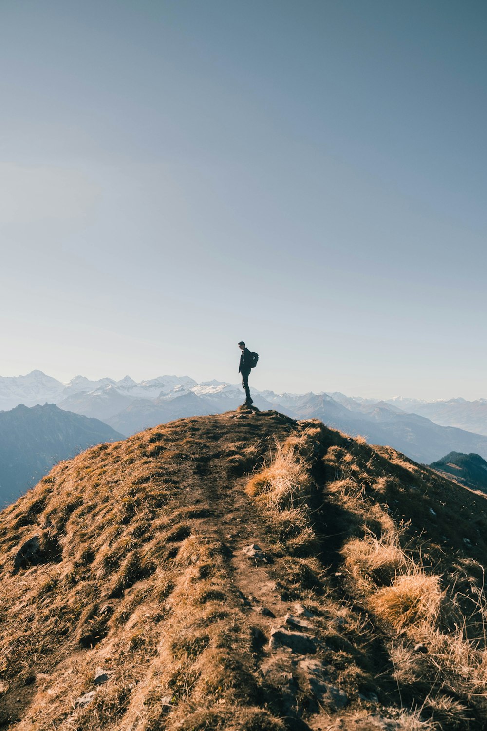 Persona in piedi sulla montagna di roccia marrone durante il giorno