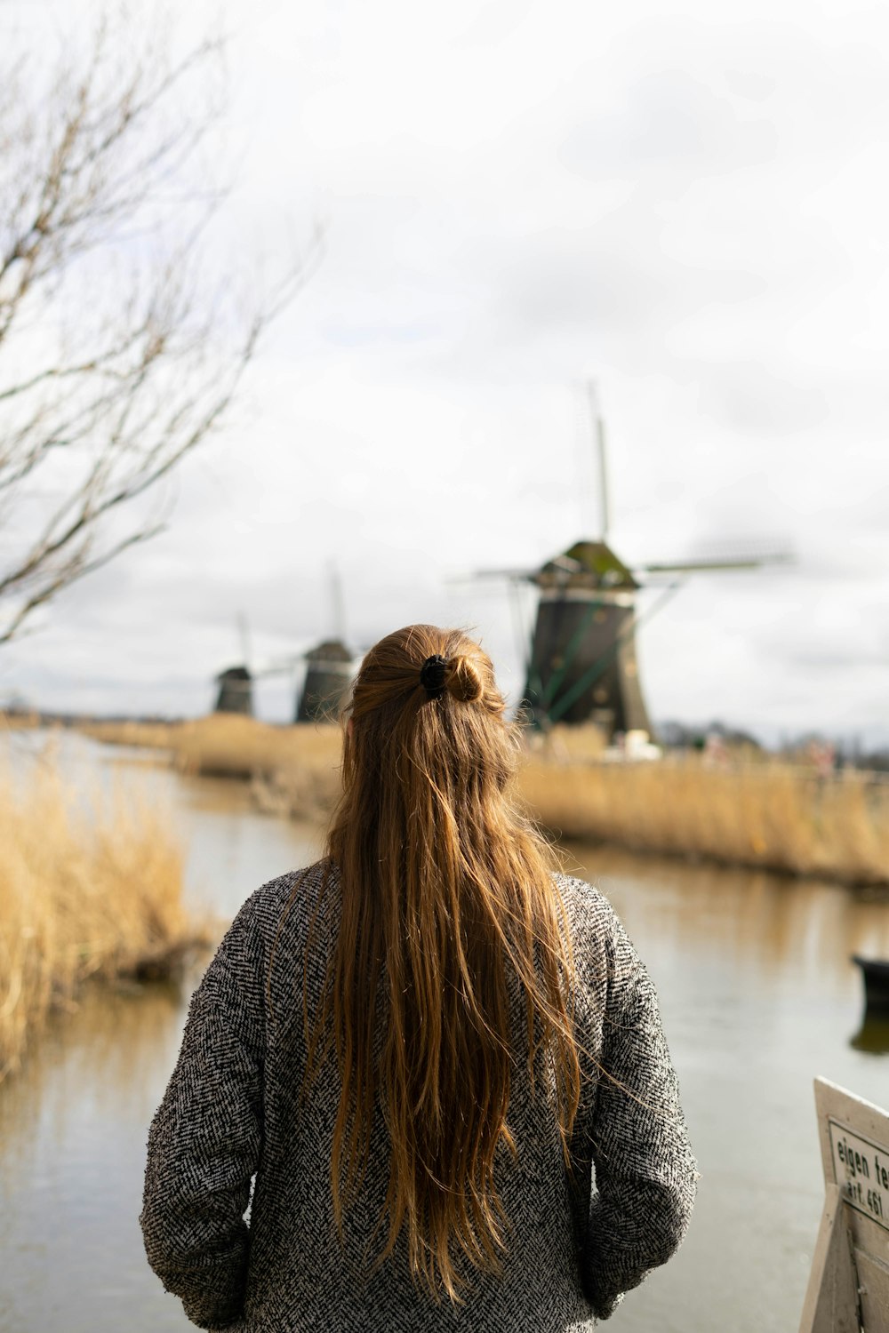 woman in black and gray sweater standing near body of water during daytime