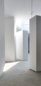 White walls and stone floor in a sunlit minimalist gallery space