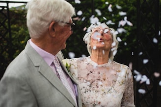 an senior couple renewing their vows, she is blowing the confetti while he is laughing