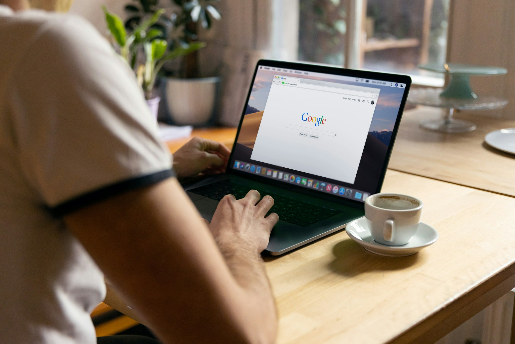 Man uses Apple MacBook in a cafe or restaurant. He is searching Google website. 