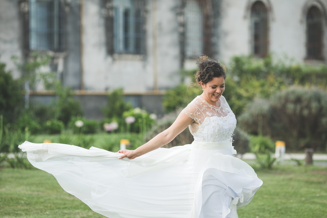 woman in white wedding dress walking on green grass field during daytime