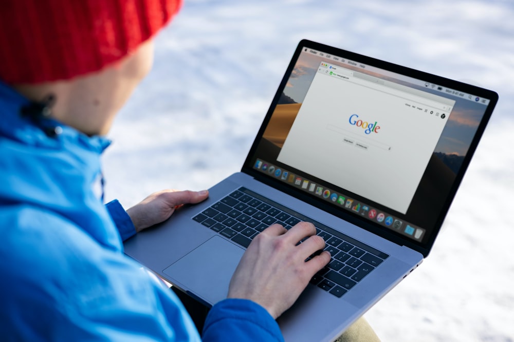 person in blue long sleeve shirt using macbook pro