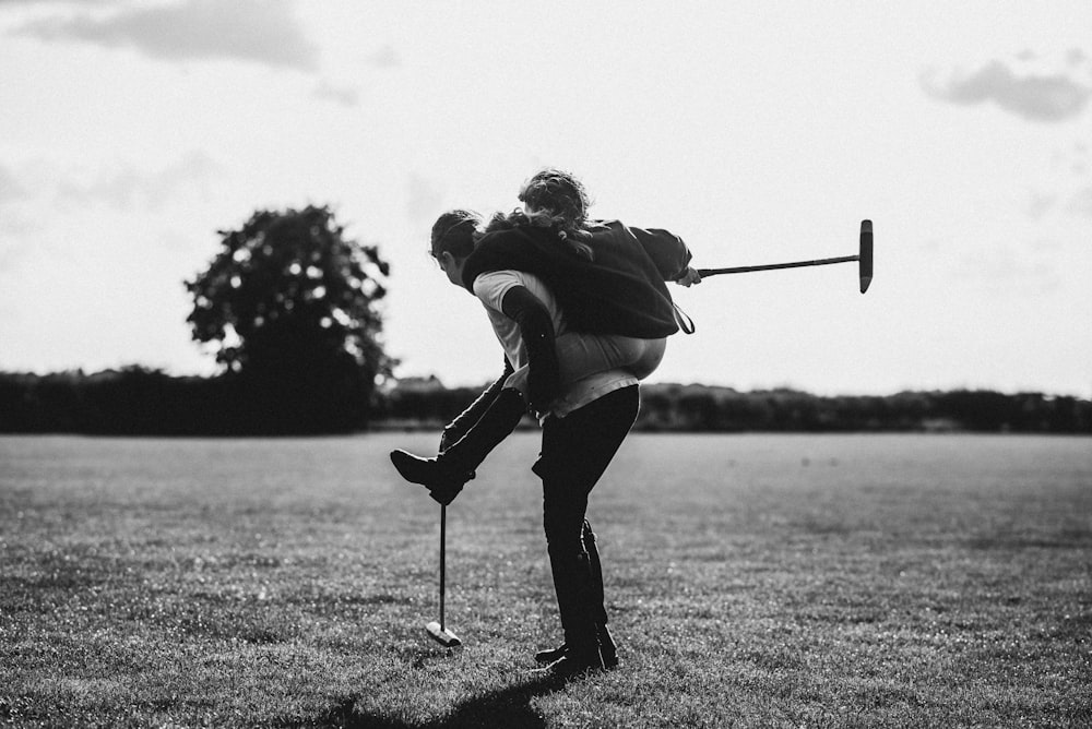 grayscale photo of woman in white long sleeve shirt and black pants playing golf