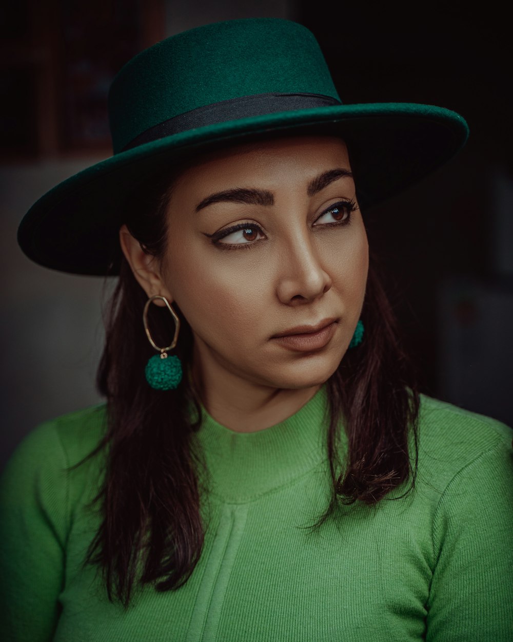 woman in green shirt wearing brown fedora hat