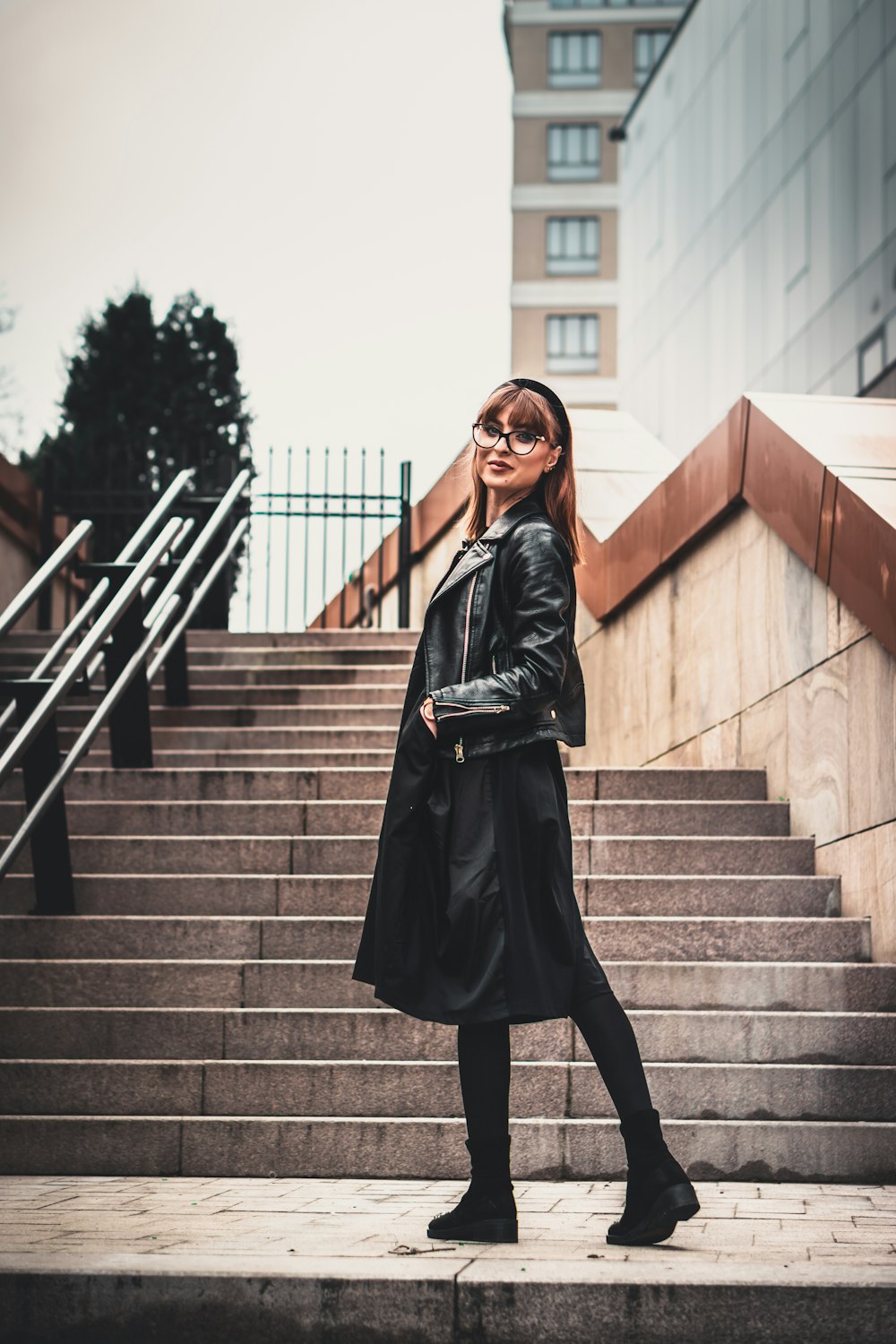 woman in black leather jacket standing on stairs