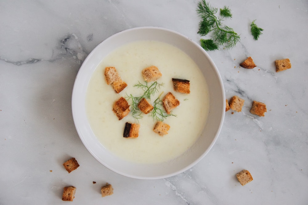 Suppe mit grünem Blatt auf weißer Keramikschale