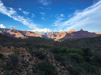 green trees and brown mountains under blue sky and white clouds during daytime