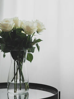 A minimalist red rose bouquet in a sleek black vase on a white marble surface