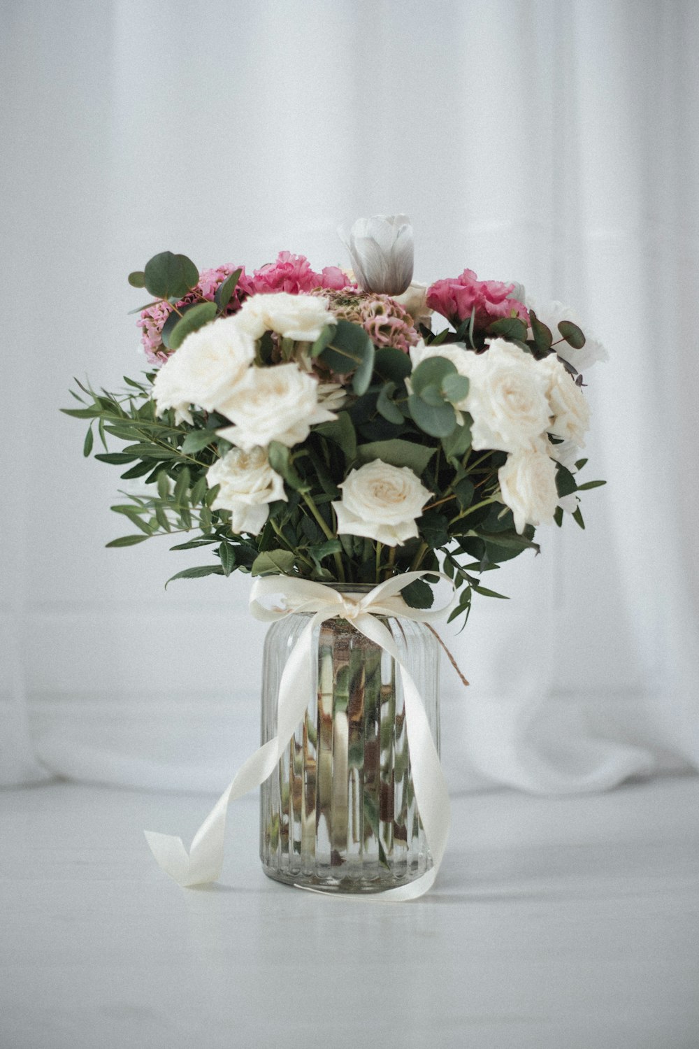weiße und rosa Blumen in klarer Glasvase