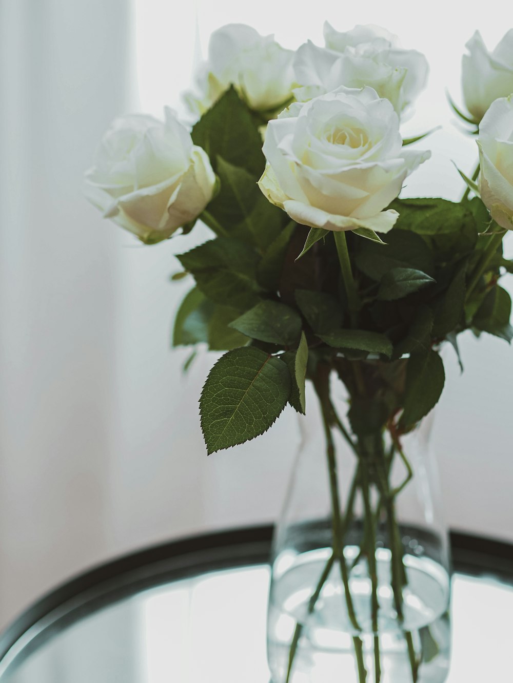 white roses on clear glass vase