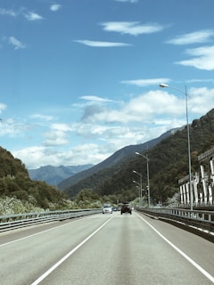 A freshly paved highway winding through the lush hills of Jammu & Kashmir under a clear blue sky