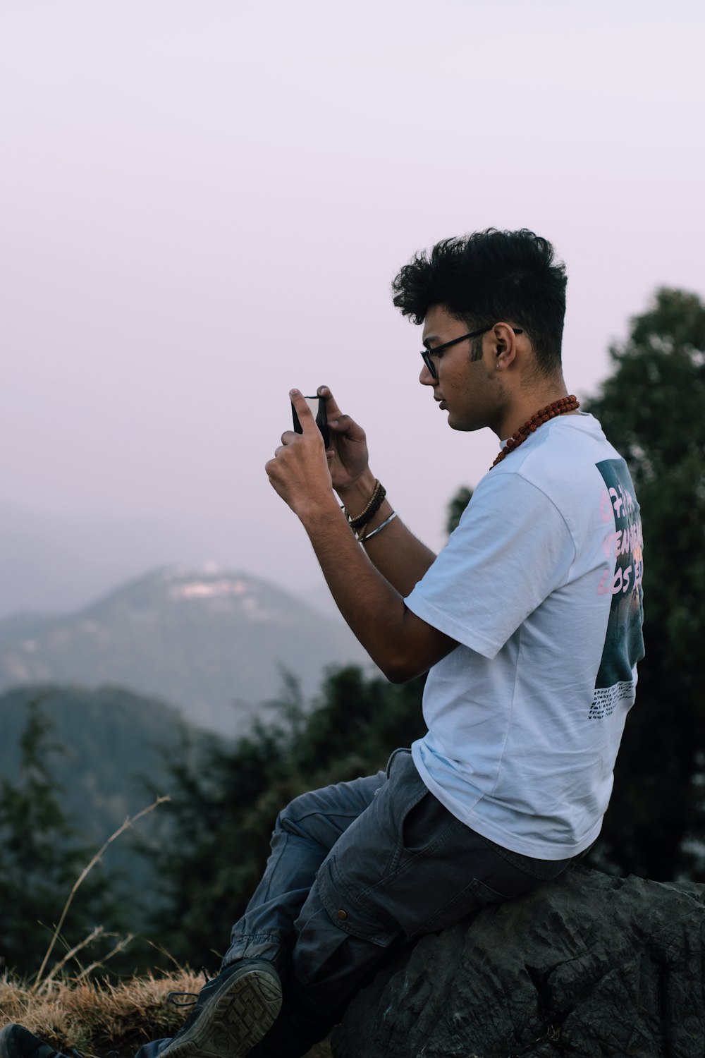 man in white polo shirt and blue denim jeans holding smartphone