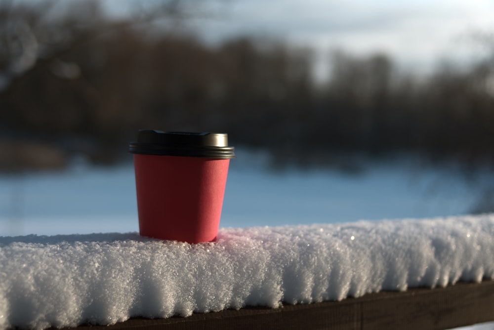 red and black travel mug on white snow