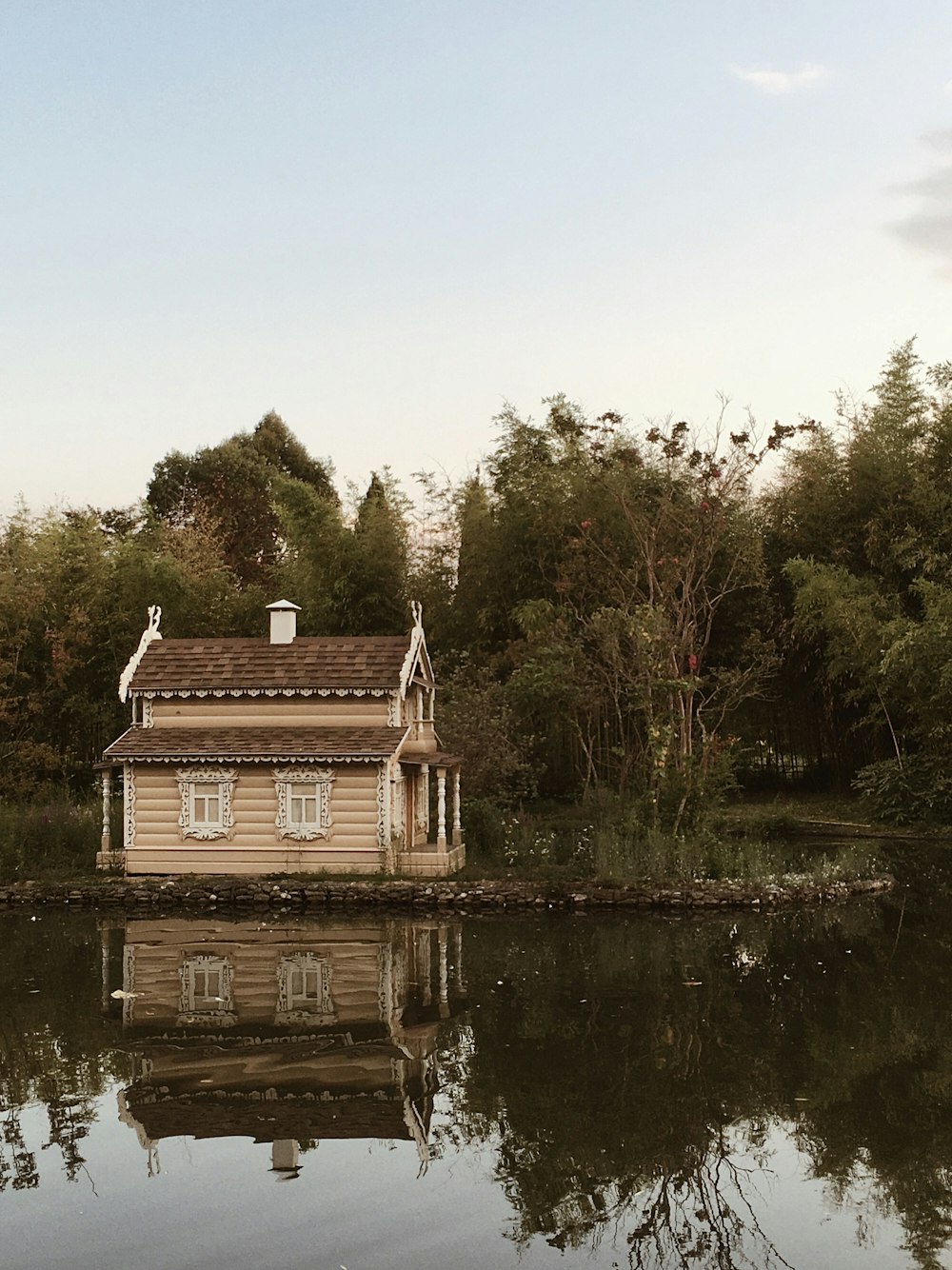 brown and white house near green trees and lake during daytime