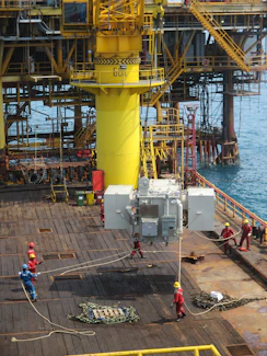 Industrial logistics team coordinating operations in a rugged Angolan oilfield setting under clear skies.