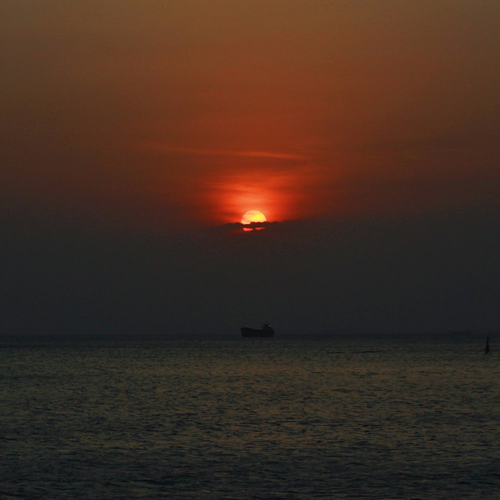 silhouette of boat on sea during sunset