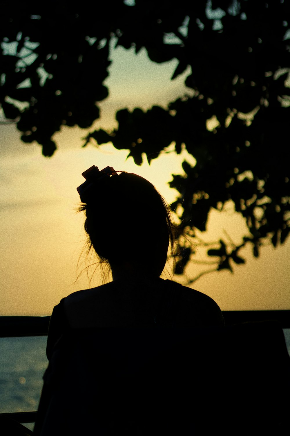 silhouette of woman near body of water during sunset