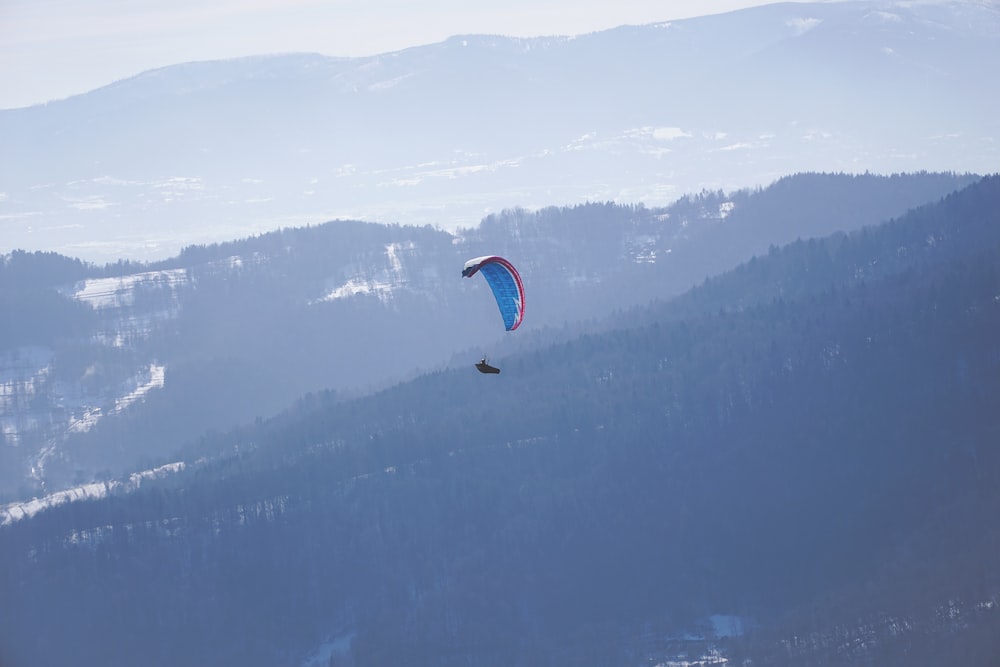 person in parachute over the mountains during daytime
