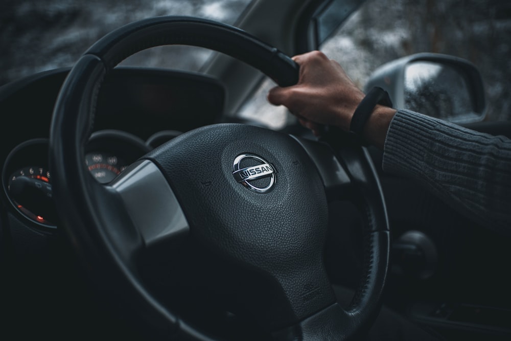 person holding black nissan steering wheel