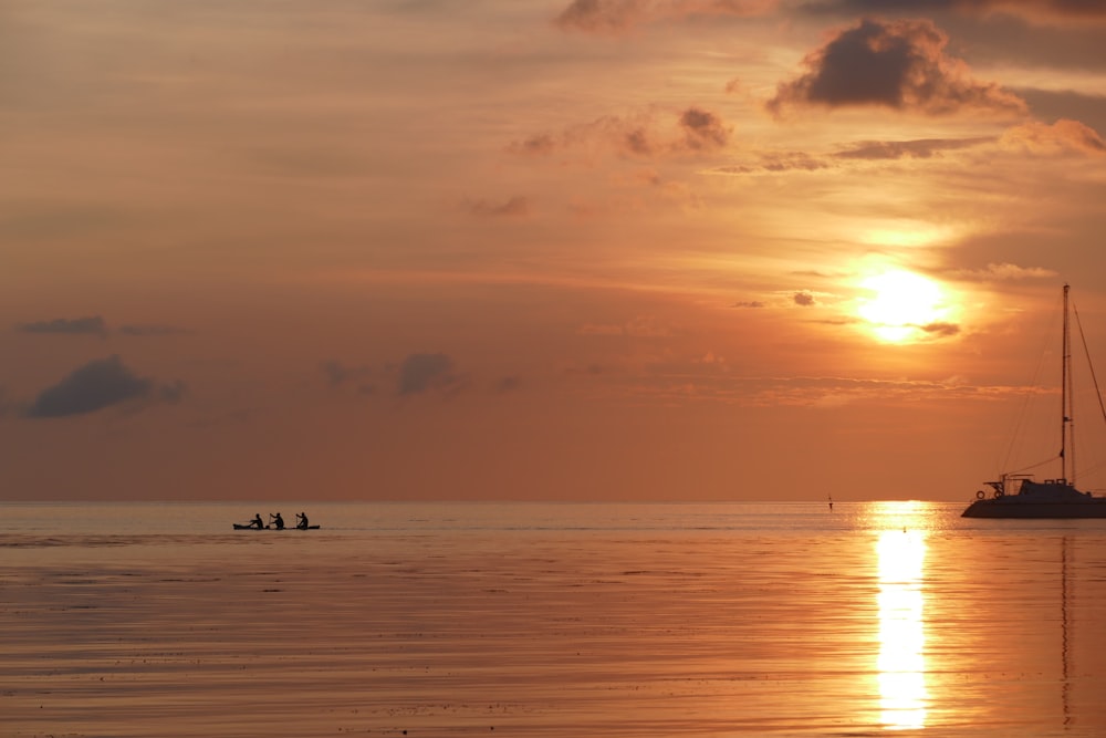 silhouette of person riding boat on sea during sunset