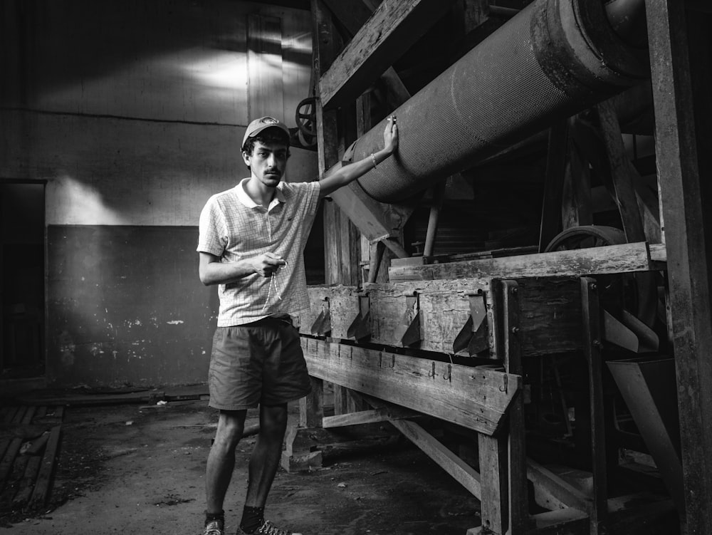 man in white long sleeve shirt and brown shorts standing near white metal tank