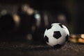 white and black soccer ball on black sand