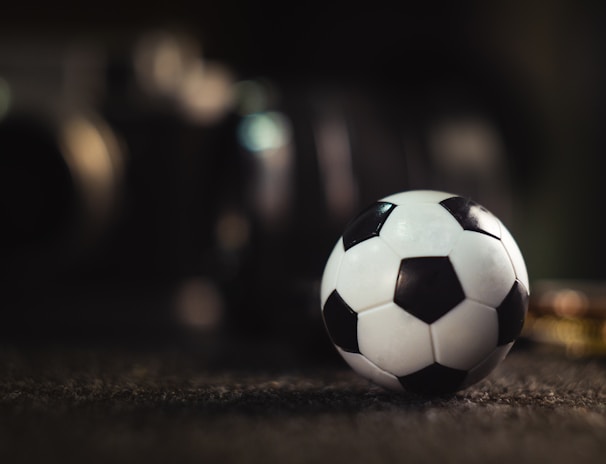 white and black soccer ball on black sand