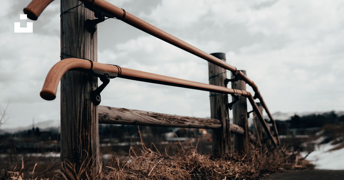 Brown metal railings on brown grass field near body of water during ...