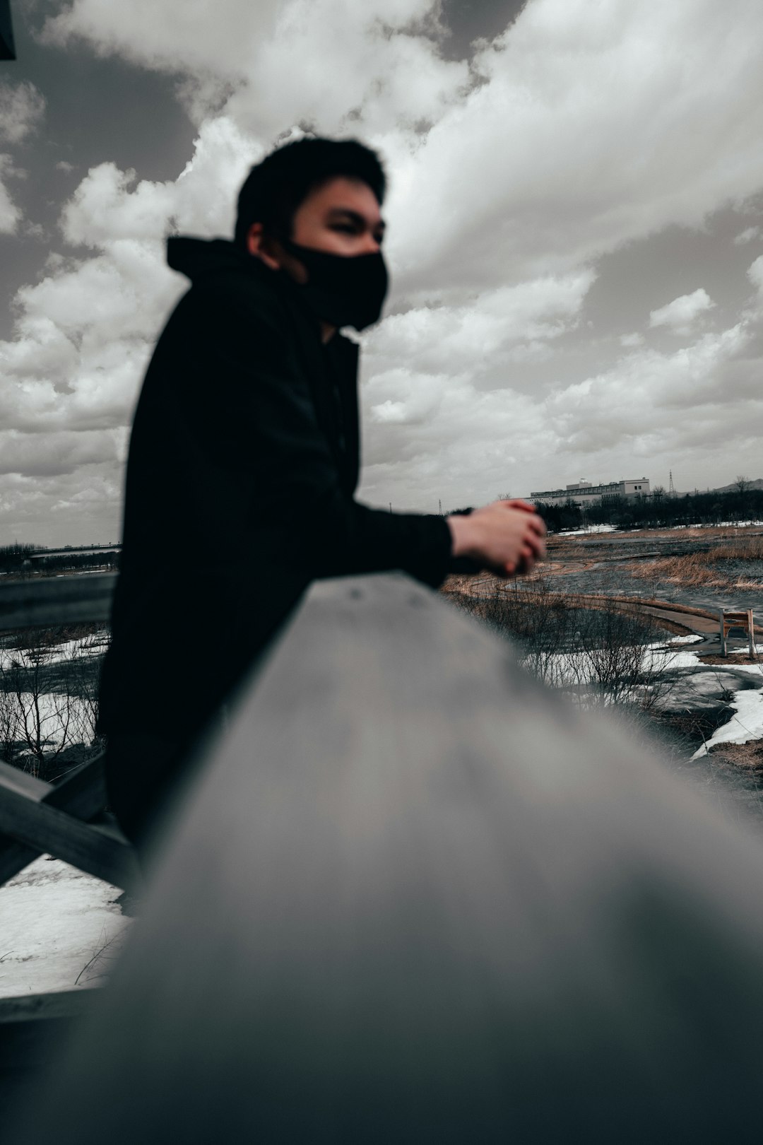 person in black hoodie standing on bridge during daytime