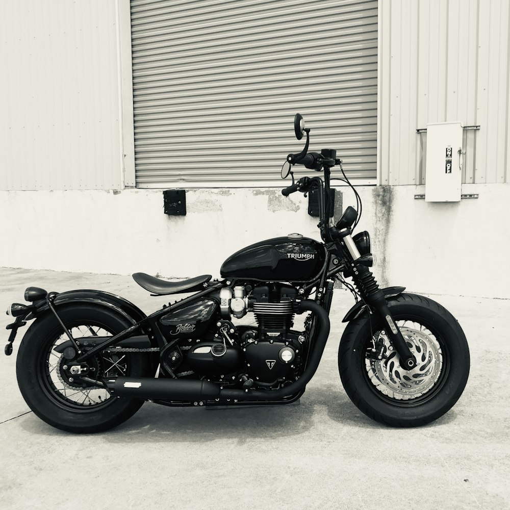 black cruiser motorcycle parked beside white wall