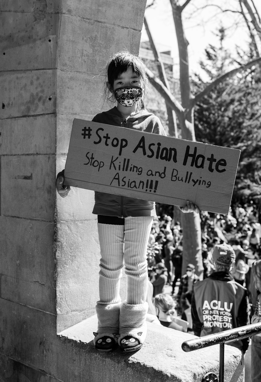 a woman holding a sign that says stop asian hate