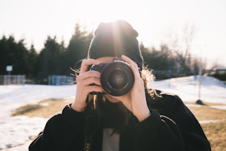 person in black jacket holding black dslr camera