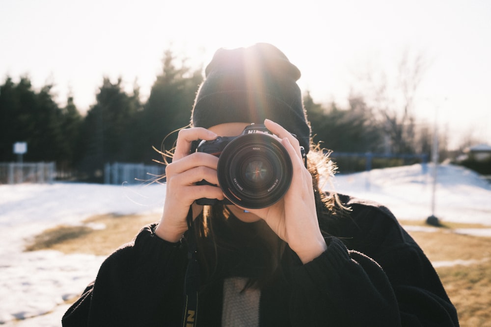 person in black jacket holding black dslr camera