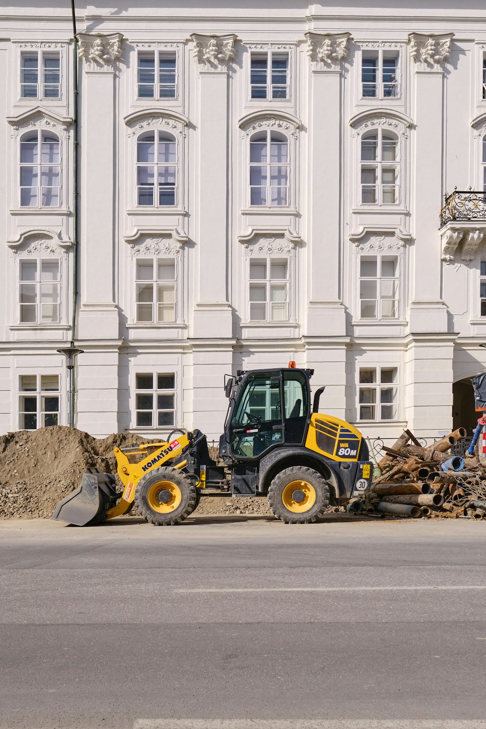 yellow and blue tractor in front of white concrete building