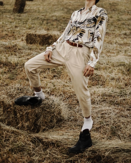 person in white pants walking on brown grass field during daytime