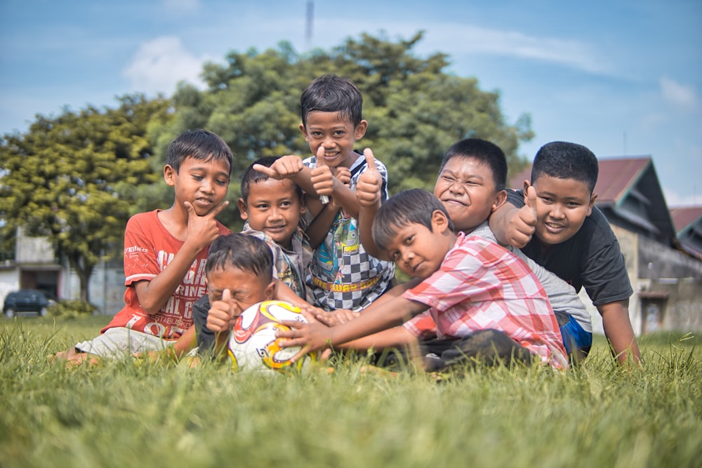 children sitting on green grass field during daytime